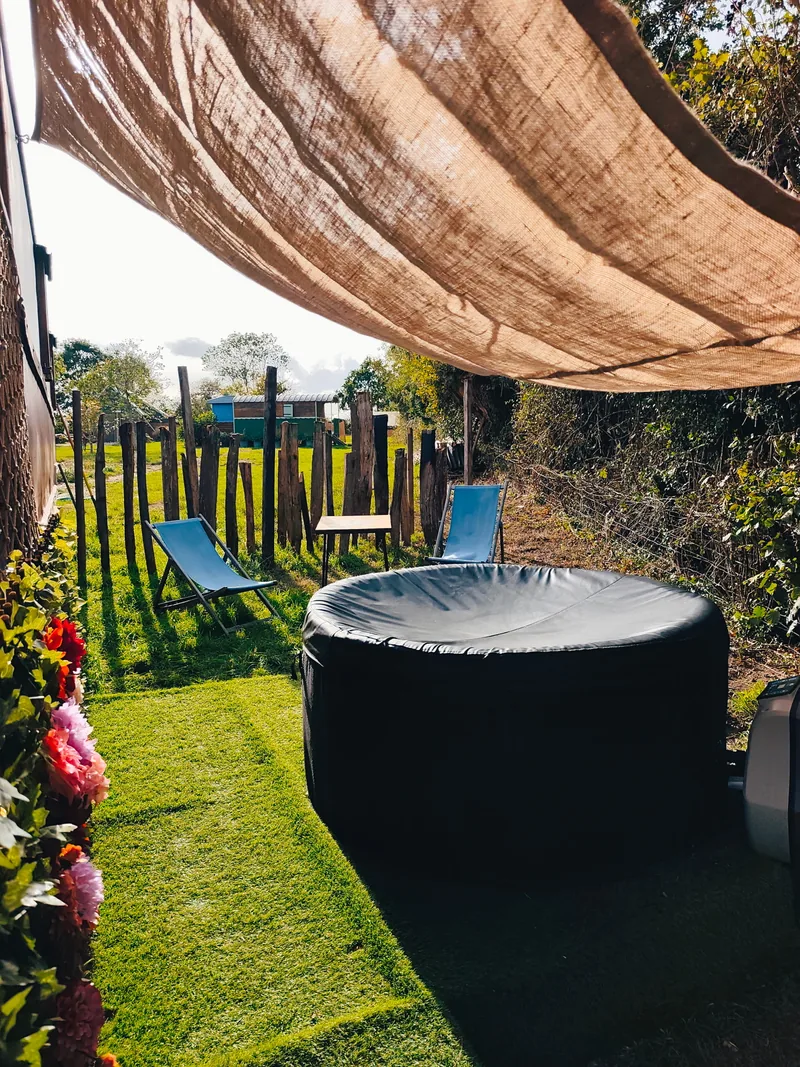 Le Luxury Circus — Le jardin privatif : le jacuzzi en plein air, les transats et la palissade de rondins