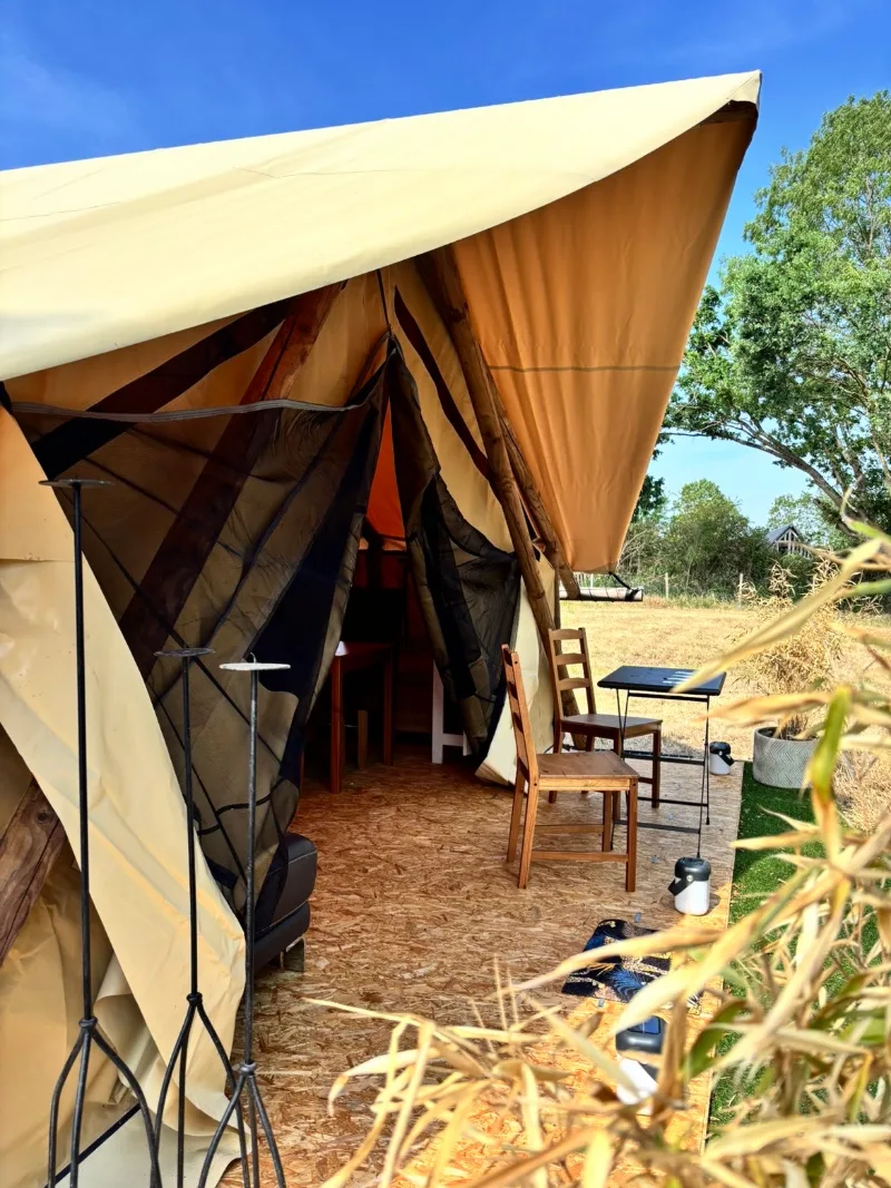La Tente safari, son auvent relevé et sa terrasse en bois avec table et chaises